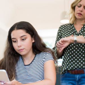 Adolescente absorbée par son smartphone et ignorant sa mère furieuse. Communication familiale entravée par les nouvelles technologies.